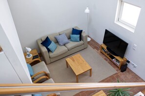 A living room with a sofa, a TV stand, a coffee table, and a plant.
