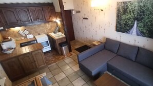 Una cucina funzionale con zona pranzo, un divano grigio e un grande murale a tema foresta.
