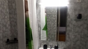 Un bagno con un lavandino bianco, uno specchio e una tenda da doccia.