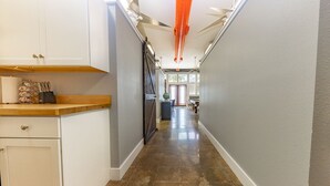 A narrow hallway with white cabinetry, a wooden countertop, and a polished stone floor.