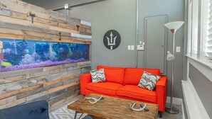A modern room with a large aquarium, a red sofa, and a wooden coffee table.