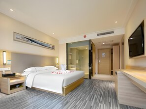 A modern hotel room with a bed, bedside table, and a large TV. - City Convenient Hotel (Yichang)