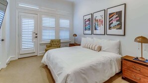 A bedroom with a large bed, a chair, a nightstand, and a ceiling fan.