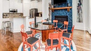 A modern kitchen with white cabinets, a central island, and a stone fireplace.