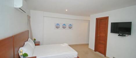 Een hotelkamer met twee bedden, een televisie, een houten deur en een wandairconditioner.