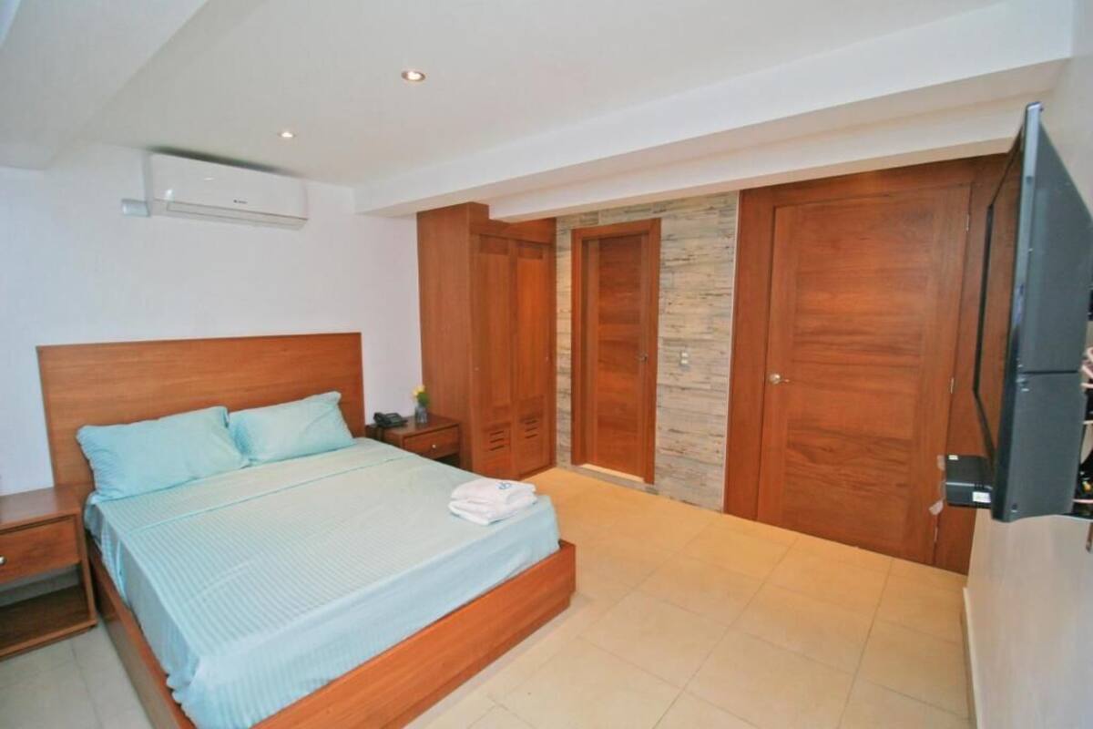 Une chambre à coucher avec un lit, une armoire en bois et un téléviseur.