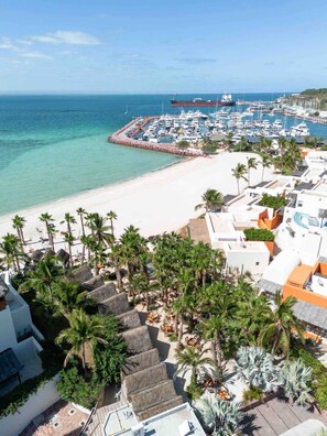 Um resort costeiro com marina, praia e caminhos bordeados por palmeiras.