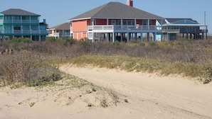 Une propriété située en bord de mer, comprenant plusieurs maisons, notamment une grande maison rouge dotée d’un balcon et une maison bleue également pourvue d’un balcon.