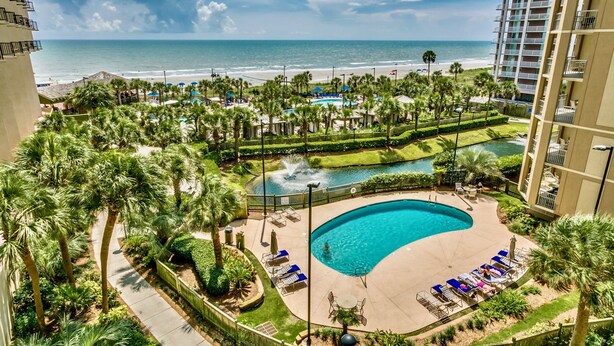 A resort with a swimming pool, beach view, and palm trees. - Royale Palms 1204 2 Br Oceanview in Kingston, Pool (Myrtle Beach)