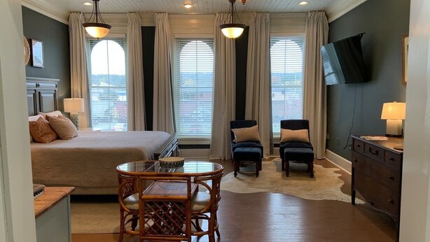 Ein Hotelzimmer mit Bett, Esstisch mit Stühlen, Fernseher und Schreibtisch mit Lampe.