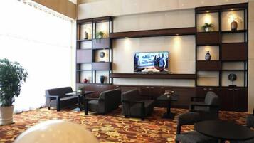 Un hall con un televisor de pantalla plana grande, zona de estar y estantes decorativos.