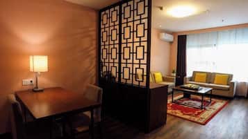 Una sala de estar con una mesa de madera, un sofá, una mesa auxiliar y un separador decorativo.
