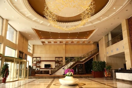 A spacious lobby with a grand chandelier, a reception desk, and a staircase leading to upper floors.. Ripple Hotel (Weihai Wendeng Bus Station)