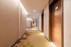 A hotel corridor with wooden doors, carpeted flooring, and recessed lighting. - Ripple Hotel (Weihai Wendeng Bus Station) (Weihai)