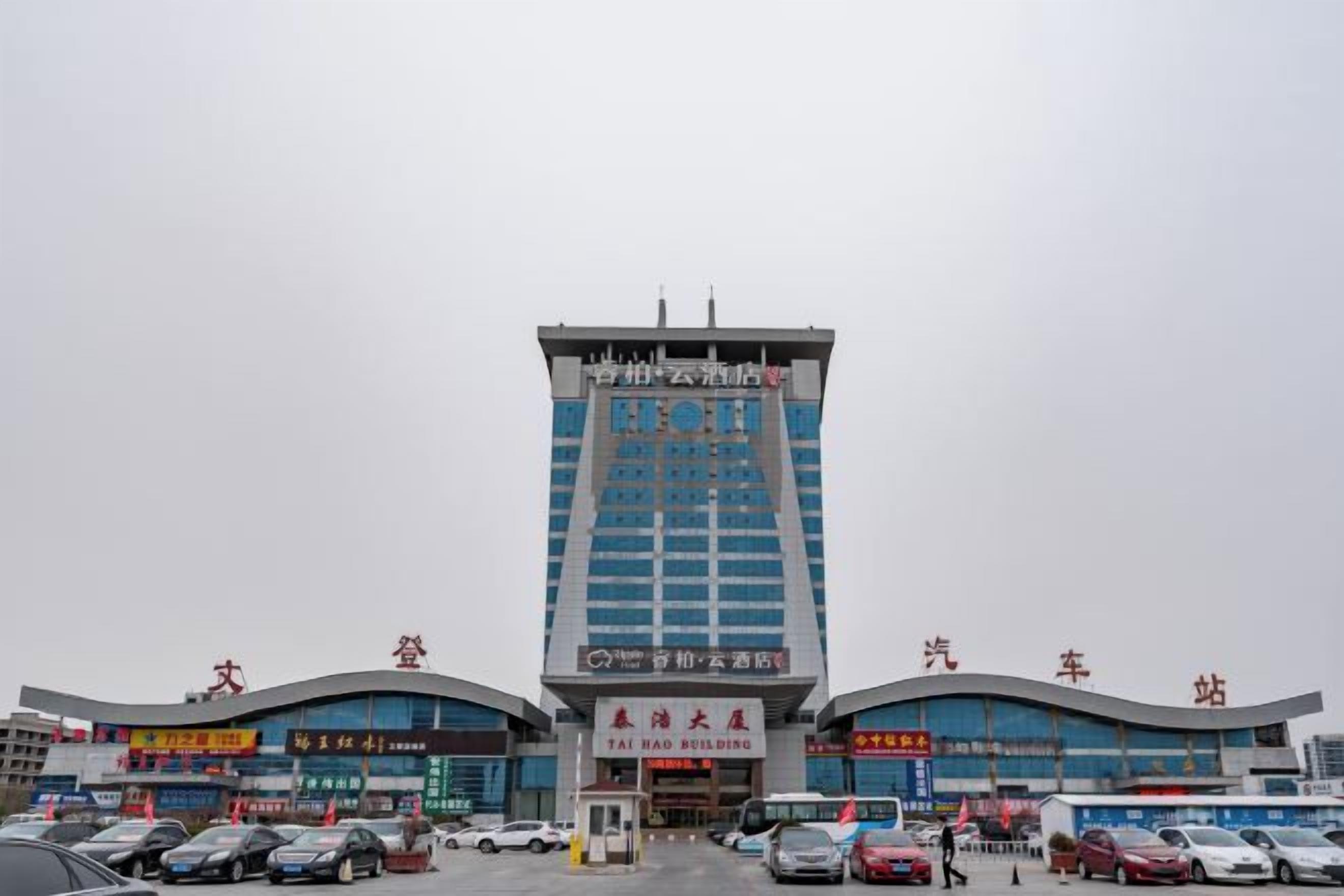 Ein mehrstöckiges Gebäude mit einem markanten Eingang und Beschilderung für ein Hotel und eine Autohaus.