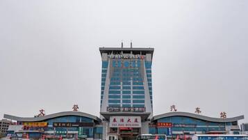 A multi-story building with a prominent entrance and signage for a hotel and a car dealership.
