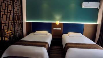 Habitació d'hotel amb dos llits, un panell decoratiu a la paret, aire condicionat fixat a la paret i un lluminari de paret.