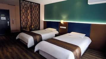 Habitación de hotel con dos camas, un separador decorativo, aire acondicionado montado en la pared y suelo de madera.