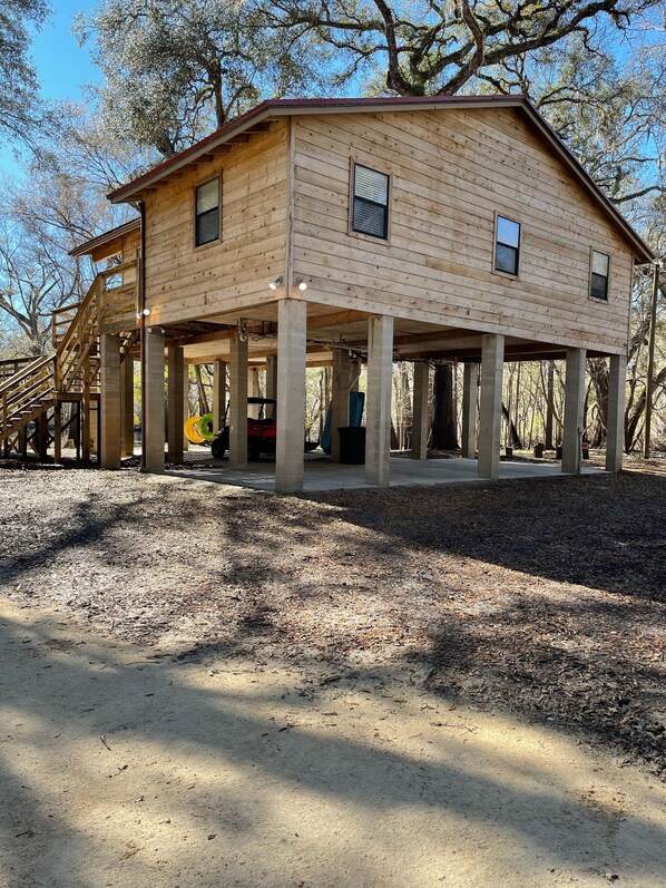 A wooden house with a covered porch and a staircase leading to the upper level. - River Run Riviera (Branford)