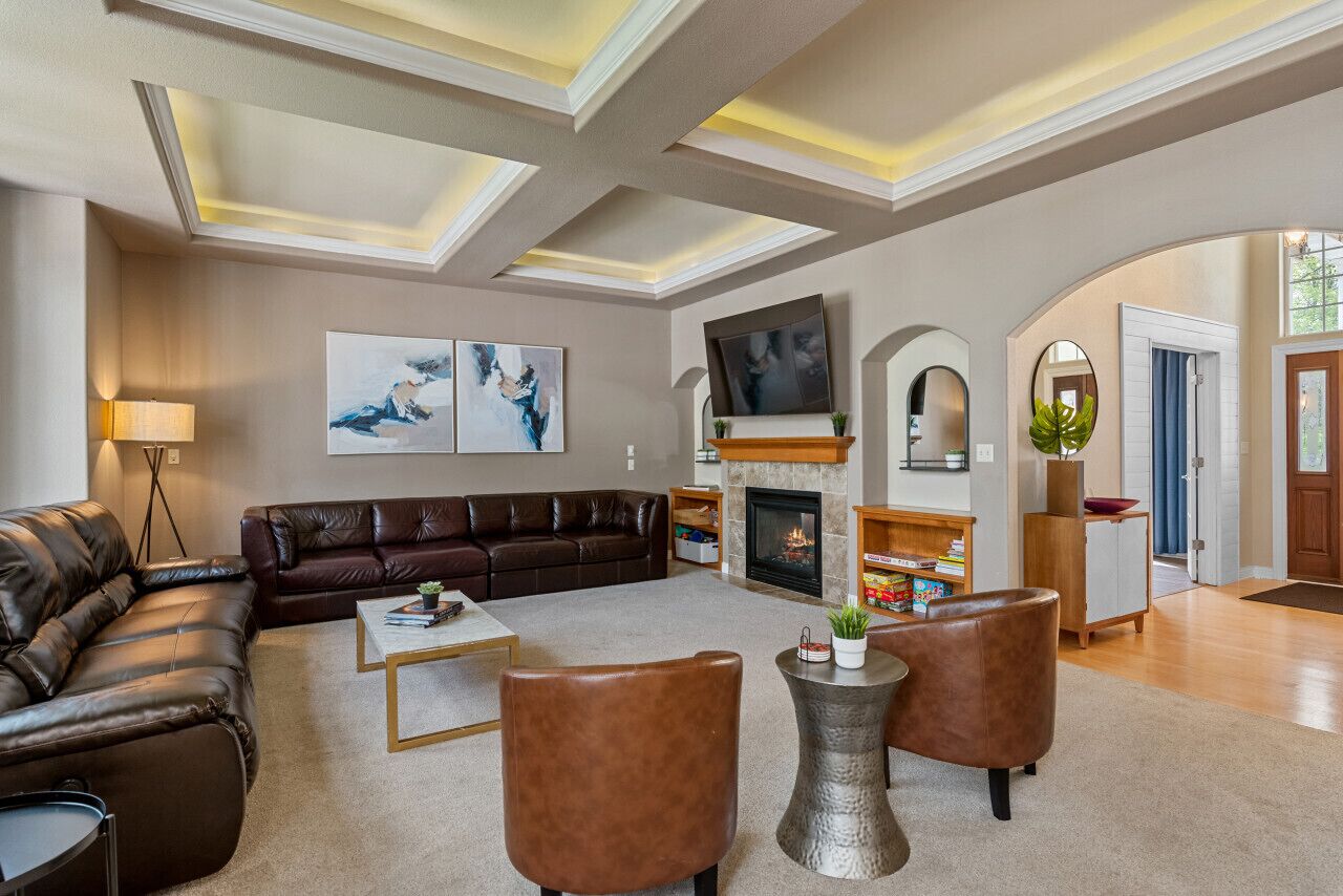 Un salon spacieux doté d’une cheminée, de canapés en cuir et d’un design moderne au niveau du plafond.
