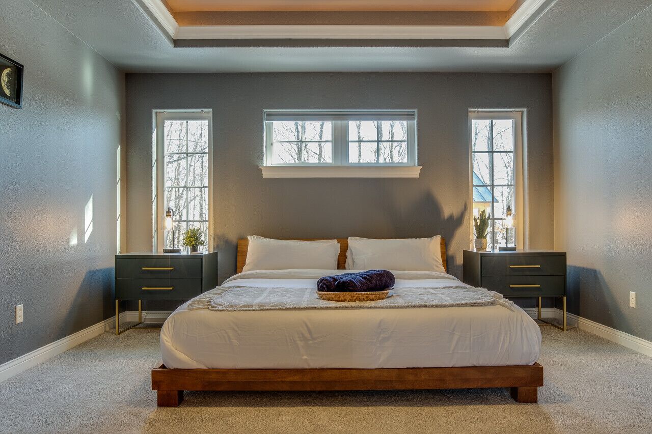 Une chambre avec un grand lit, deux tables de chevet, une fenêtre et un plafond doté d’une lucarne.