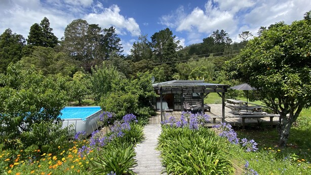A garden with a pool, a gazebo, and a pathway lined with flowers. - Tiny Studio - Near New (Whangamatā)