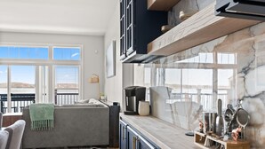 A modern kitchen with a marble countertop, built-in cabinets, and a view of the outdoors. - The Eastside ~ Modern Coastal Getaway w/ Pool, Private Beach, Sauna and Dock (Colchester)