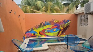 A pool area with a colorful mural, blue chairs, and a patterned rug. - Casa Tranquila- Beautiful House with a Private Pool 2 Blocks from the Ocean (San Miguel de Cozumel)