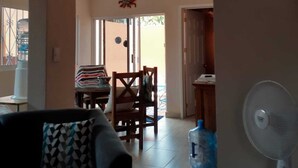 A living room with a sofa, a fan, and a dining area with a table and chairs. - Casa Tranquila- Beautiful House with a Private Pool 2 Blocks from the Ocean (San Miguel de Cozumel)