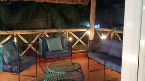 An outdoor seating area with thatched roof, cushioned seating, and a central round table. - Casa Tranquila- Beautiful House with a Private Pool 2 Blocks from the Ocean (San Miguel de Cozumel)