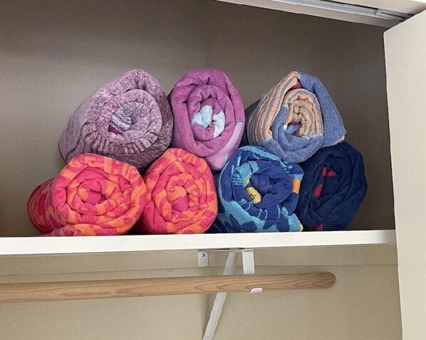 Un compartiment de rangement contenant des couvertures soigneusement pliées, de différentes couleurs.