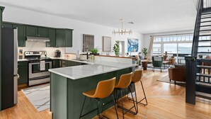 A modern kitchen with a central island, bar stools, and a view of the ocean. - The Westside - Hot tub, Private Beach & Dock. Pet-friendly! (Colchester)