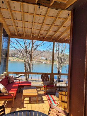 A covered outdoor seating area with a view of a lake and trees.
