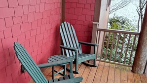 A wooden deck with two Adirondack chairs and a red brick wall. - Serendipity 22 (Branson)