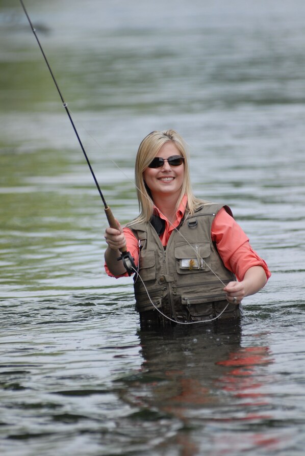A person standing in water, holding a fishing rod.