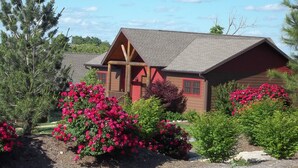 A rustic cabin with a sloped roof, wooden beams, and a red door. - Serendipity 22 (Branson)