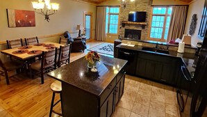 A spacious kitchen with a large island, wooden ceiling, and stone fireplace. - Serendipity 22 (Branson)