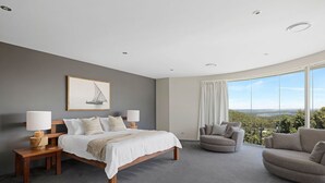 A modern bedroom with a large bed, two bedside tables, a chair, and a sofa. - Grandview - Luxurious Entertainer with Spectacular Views (Nelson Bay)