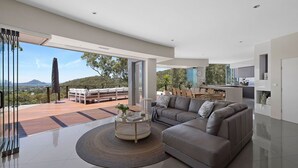 A modern living room with a large sofa, a coffee table, and a view of the outdoors. - Grandview - Luxurious Entertainer with Spectacular Views (Nelson Bay)