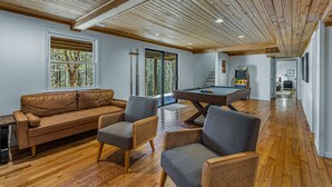 Un vaste espace de vie doté d’un plafond en bois, d’une table de billard et d’un canapé en cuir.