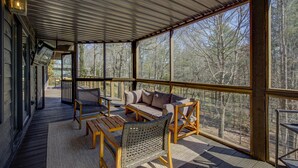 Un espace extérieur abrité, aménagé avec un banc en bois, une chaise en osier et un canapé rembourré.