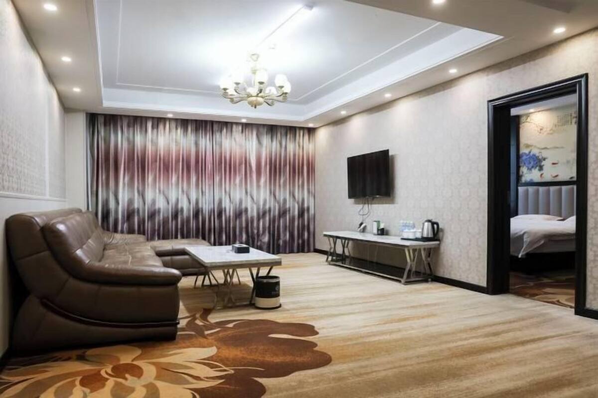 Una habitación de hotel con sofá, mesa de comedor, televisor y cama.