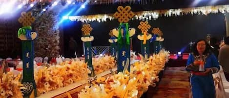 A decorated aisle with floral arrangements and columns, a chandelier, and a person standing in the aisle.