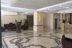 A lobby with a marble floor, sofas, a reception desk, and a decorative pillar. - He Qi Boutique Hotel (Harqin Banner)