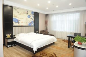 A hotel room with a large bed, a desk, a chair, and a potted plant. - He Qi Boutique Hotel (Harqin Banner)