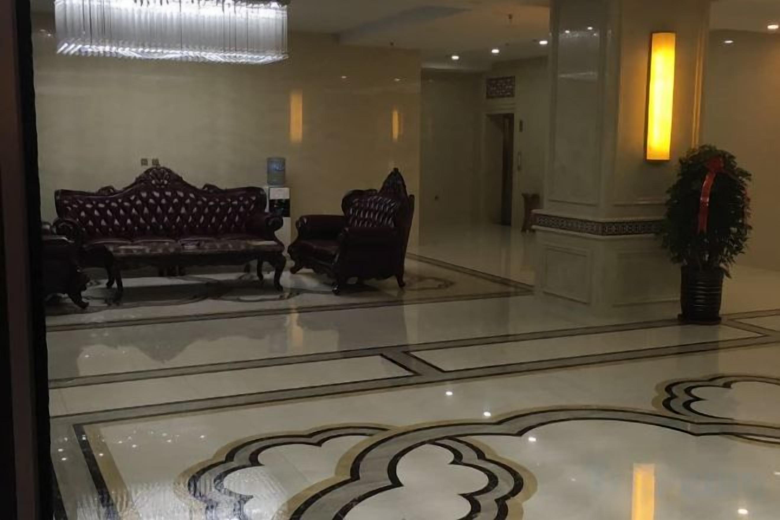 A lobby with a patterned floor, a sofa, chairs, and a potted plant.