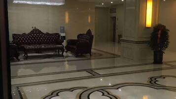 A lobby with a patterned floor, a sofa, chairs, and a potted plant.