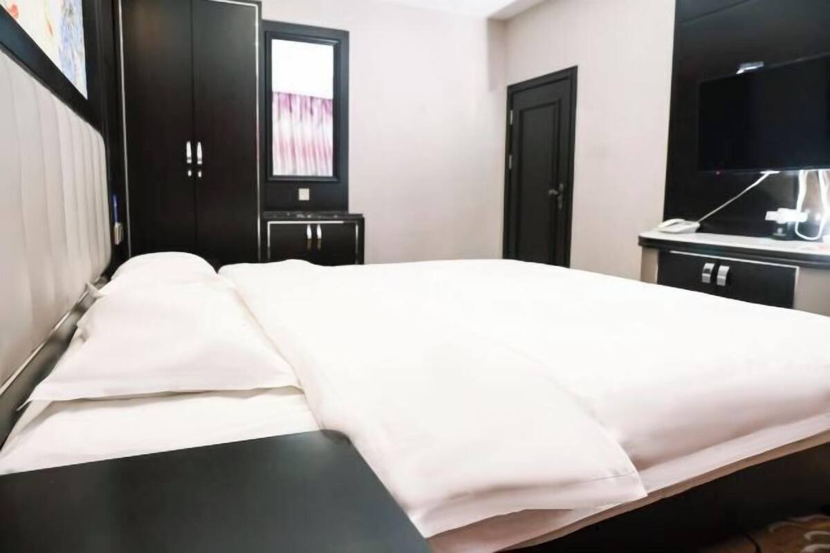 Habitación de hotel con cama, escritorio, televisor y armario.