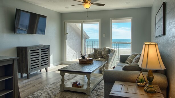 A living room with a wooden coffee table, a sofa, a lamp, and a TV mounted on the wall.