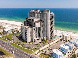 Un hôtel de grande hauteur, avec de nombreux étages, une vue sur la plage et un parking.